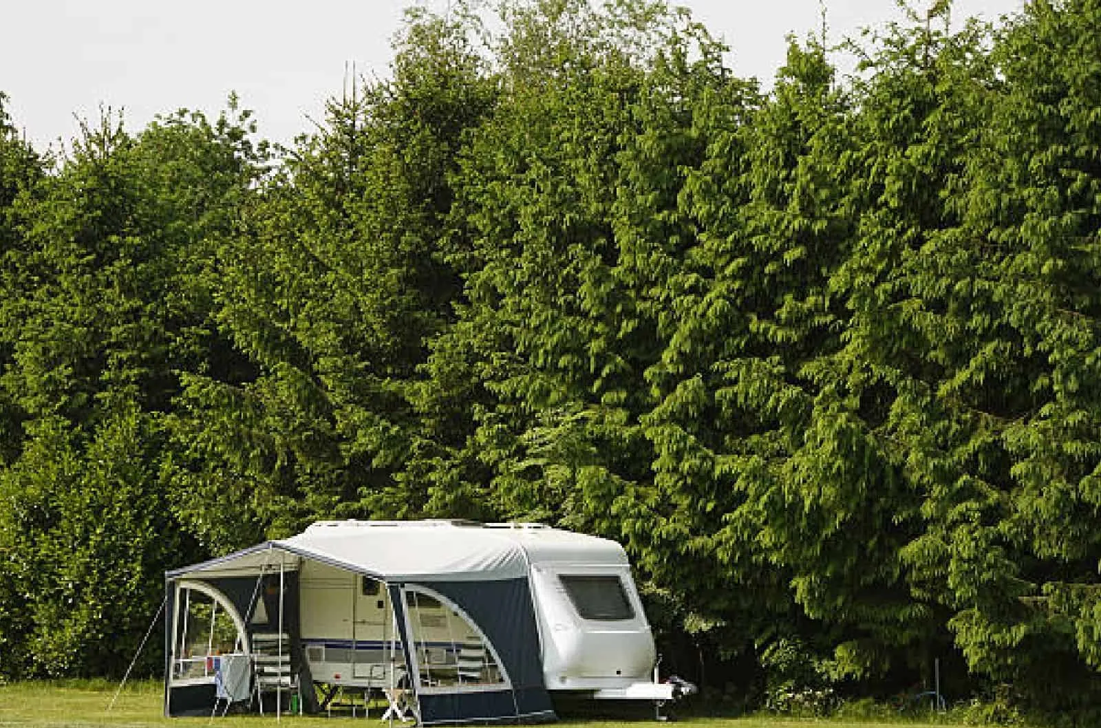 Stationärer Mietwohnwagen mit Vorzelt auf der Wiese